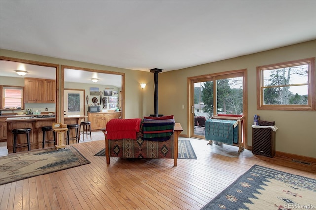 living room featuring light wood-type flooring, a wood stove, and visible vents