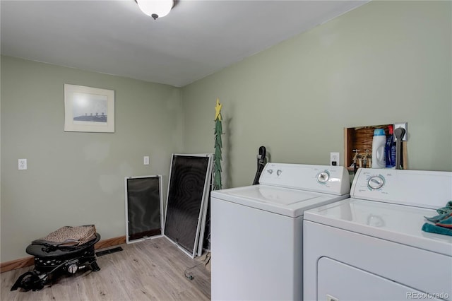 laundry area with baseboards, laundry area, washer and clothes dryer, and light wood-style flooring