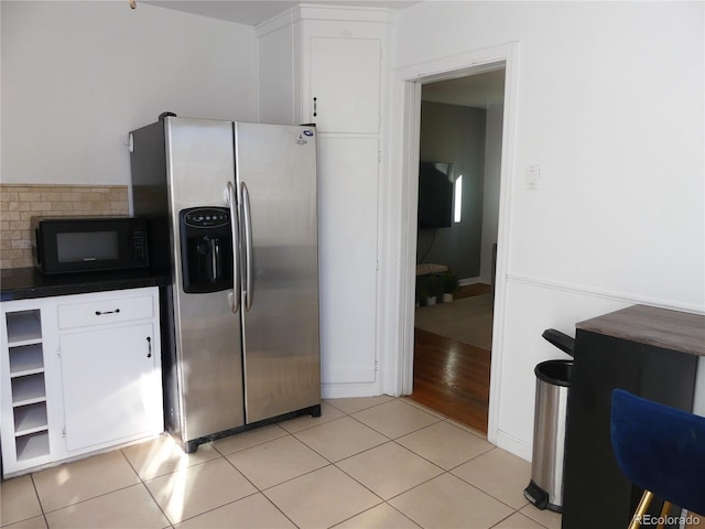 kitchen with stainless steel fridge, light tile patterned floors, and white cabinets