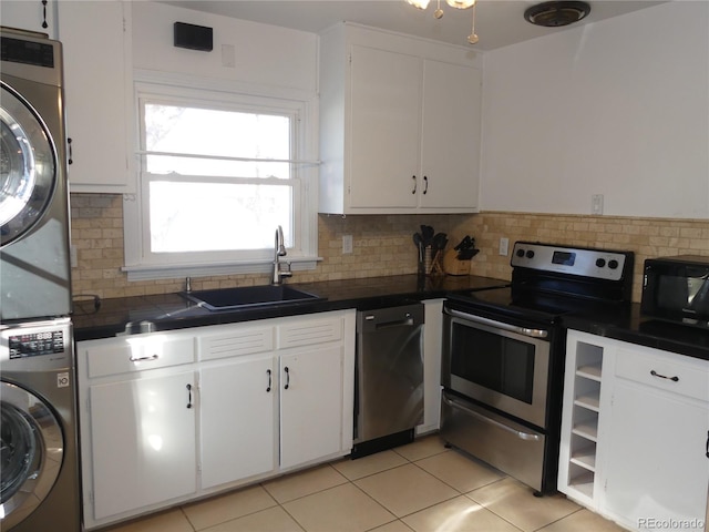 kitchen with stacked washing maching and dryer, appliances with stainless steel finishes, white cabinetry, sink, and decorative backsplash