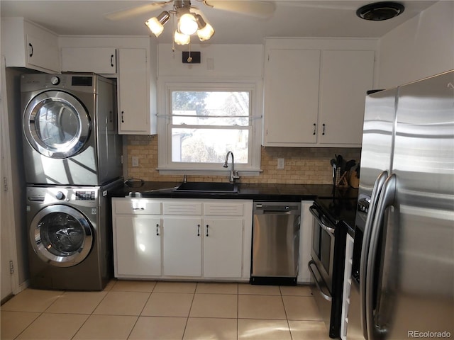 kitchen with sink, white cabinetry, tasteful backsplash, stainless steel appliances, and stacked washing maching and dryer