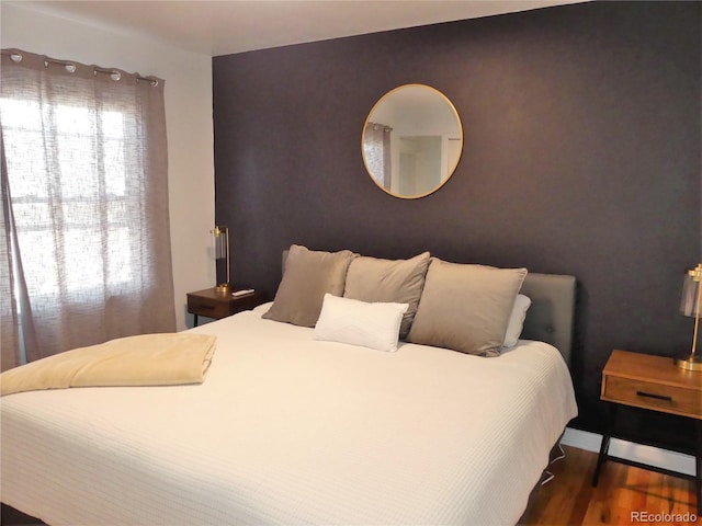 bedroom with multiple windows and dark hardwood / wood-style flooring