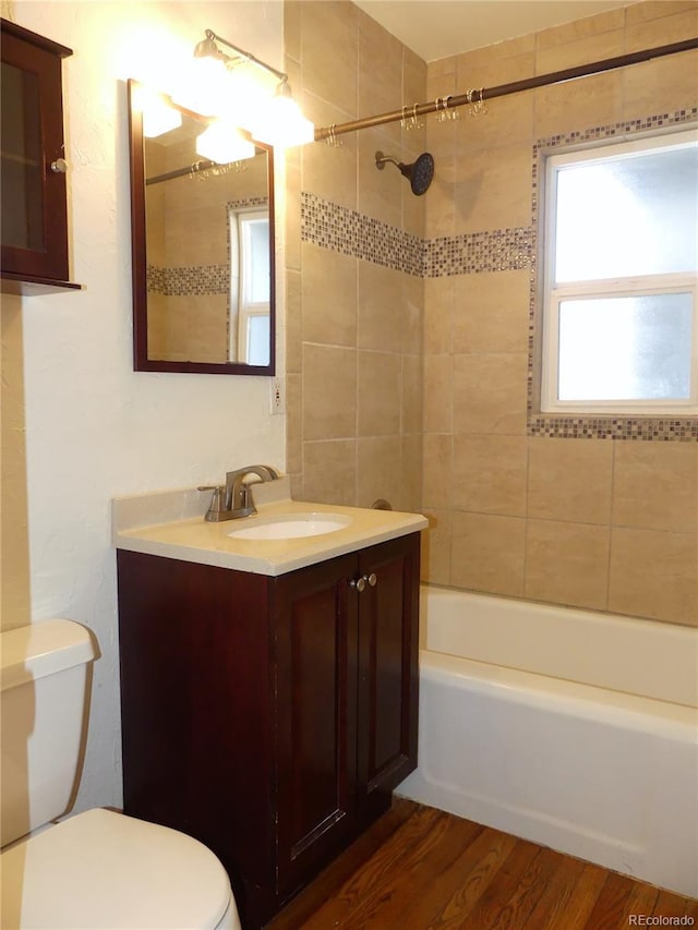 full bathroom with vanity, toilet, tiled shower / bath combo, and hardwood / wood-style floors