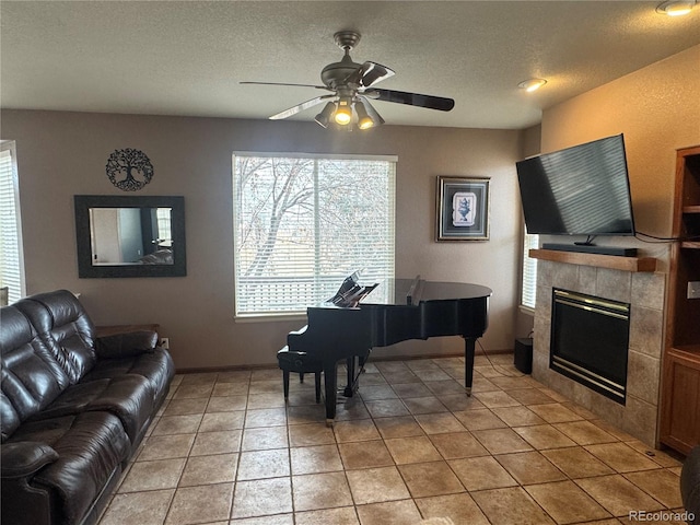 tiled living room featuring ceiling fan, a tiled fireplace, a wealth of natural light, and a textured ceiling