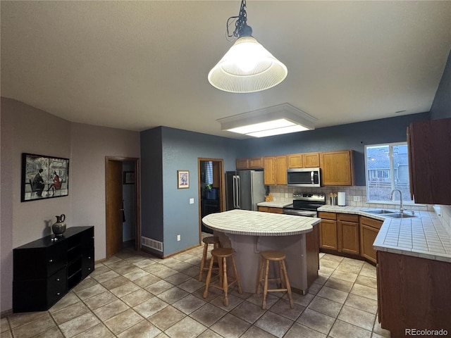 kitchen with a center island, pendant lighting, a breakfast bar, sink, and stainless steel appliances