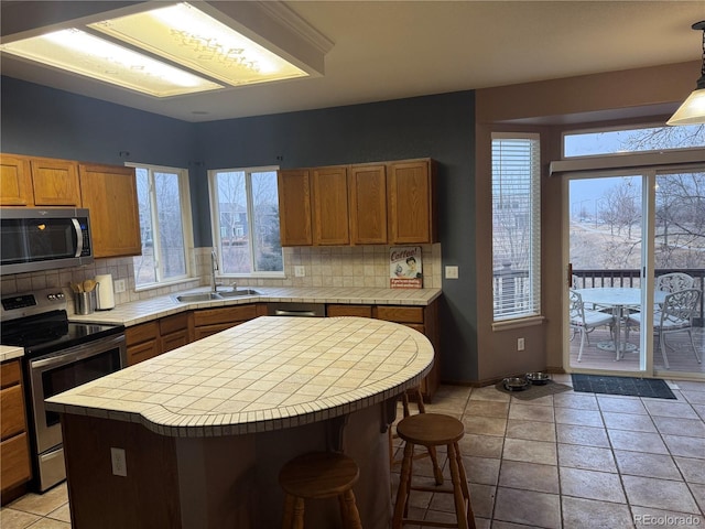 kitchen with plenty of natural light, sink, stainless steel appliances, and a kitchen island