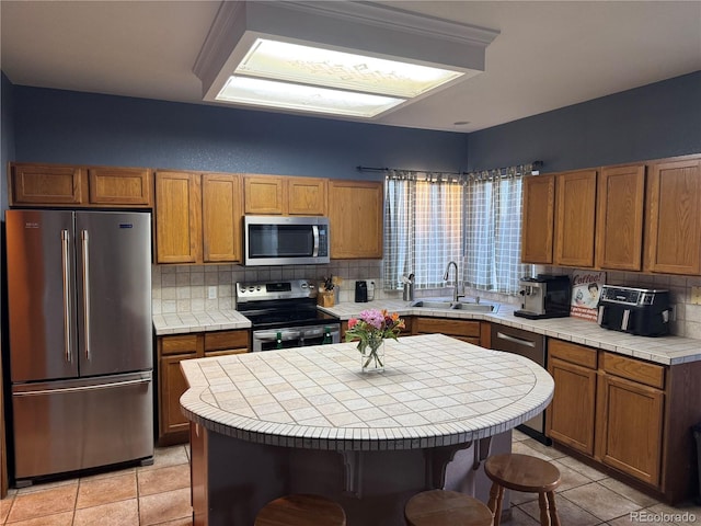 kitchen featuring appliances with stainless steel finishes, sink, tile countertops, and a kitchen island