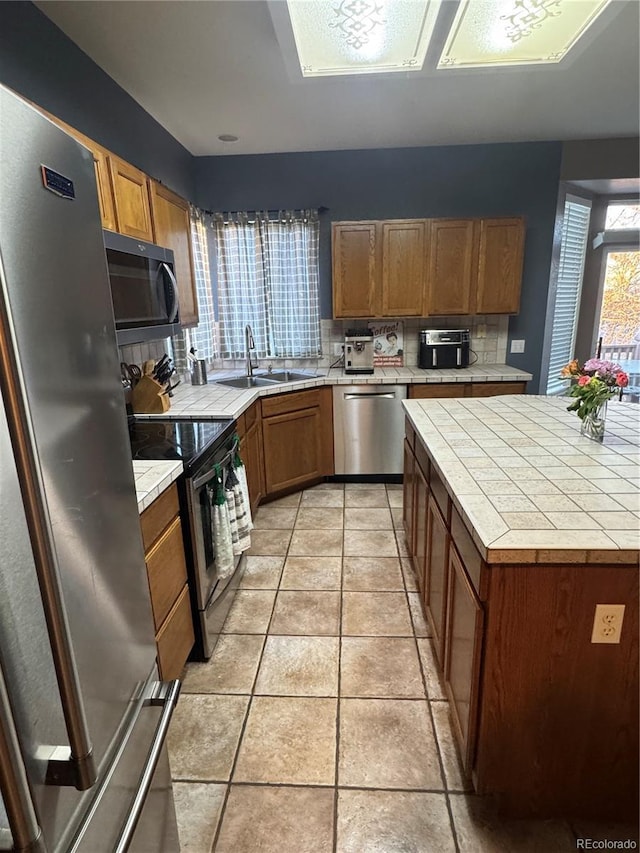 kitchen featuring light tile patterned floors, tile countertops, stainless steel appliances, tasteful backsplash, and sink