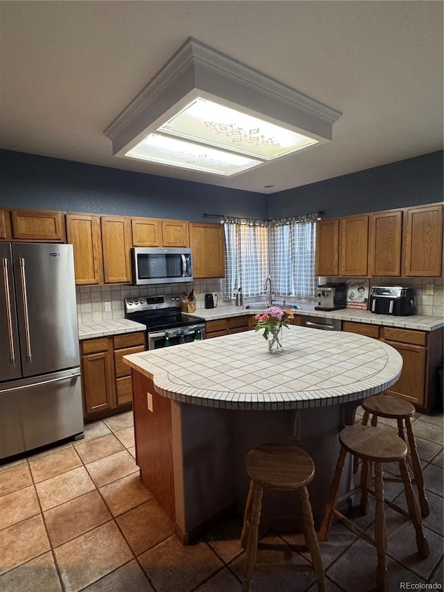 kitchen with tasteful backsplash, a center island, appliances with stainless steel finishes, a breakfast bar area, and tile counters