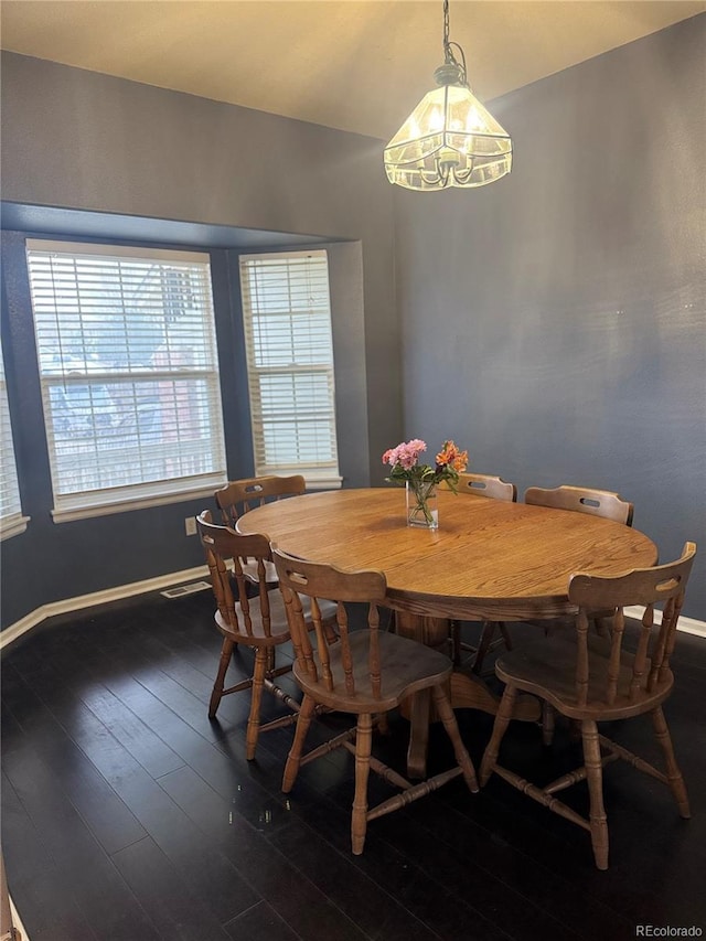 dining room with dark hardwood / wood-style floors and a notable chandelier