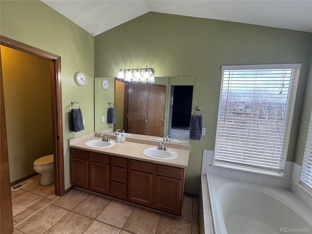 bathroom with lofted ceiling, vanity, tile patterned flooring, toilet, and a tub