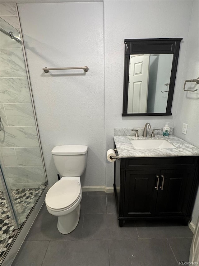 bathroom with tile patterned floors, vanity, toilet, and walk in shower