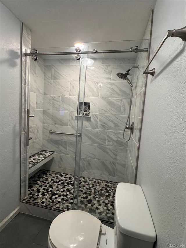 bathroom with toilet, tile patterned floors, and walk in shower