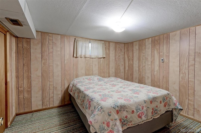 bedroom featuring dark carpet and wooden walls