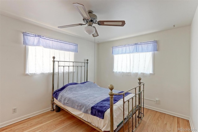 bedroom with ceiling fan, light wood-type flooring, and multiple windows