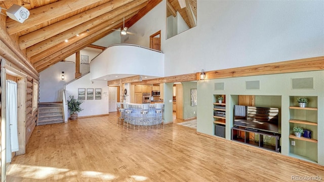 living area featuring vaulted ceiling with beams, ceiling fan, stairway, built in features, and wood finished floors