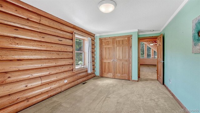 unfurnished bedroom featuring light carpet, a closet, crown molding, and baseboards