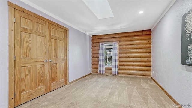 unfurnished room with baseboards, light carpet, recessed lighting, a skylight, and rustic walls