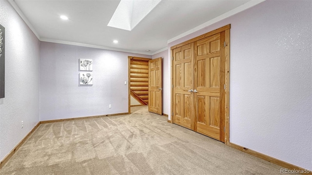 unfurnished bedroom featuring crown molding, a skylight, carpet flooring, and baseboards