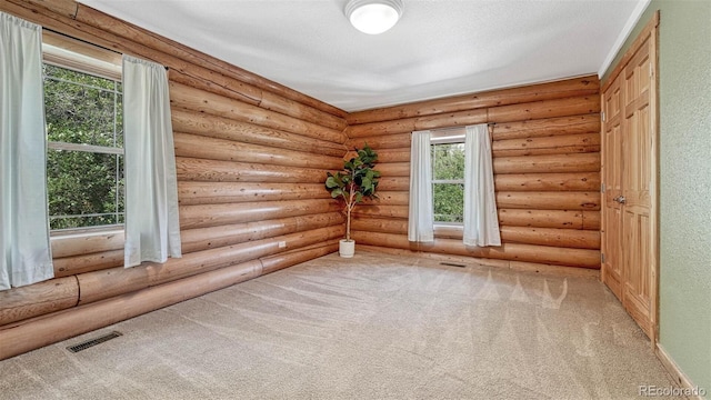 spare room with rustic walls, visible vents, carpet floors, and a textured ceiling