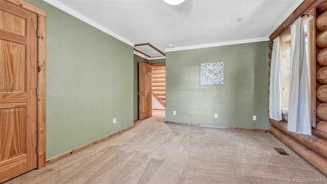 unfurnished bedroom with visible vents, baseboards, carpet, ornamental molding, and a textured wall