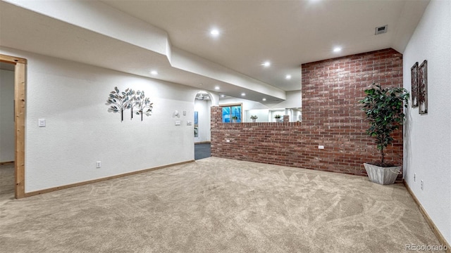 unfurnished living room featuring visible vents, recessed lighting, brick wall, carpet flooring, and baseboards