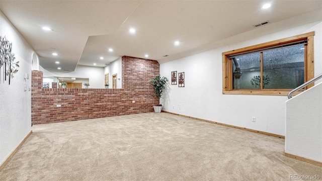 carpeted spare room featuring recessed lighting, baseboards, and brick wall