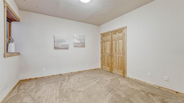 spare room with baseboards, a textured ceiling, and carpet