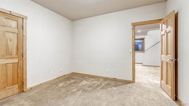 empty room with baseboards and light carpet