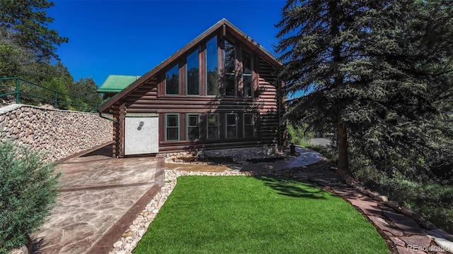 back of house featuring a patio area, a lawn, log exterior, and metal roof