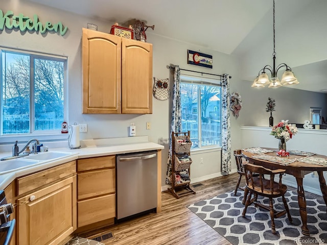 kitchen featuring light wood-type flooring, hanging light fixtures, sink, stainless steel dishwasher, and light brown cabinets