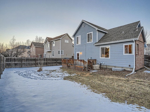 snow covered rear of property with a wooden deck