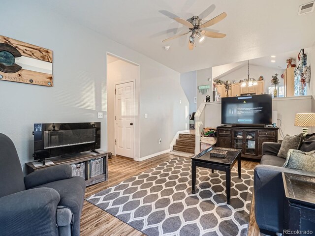 living room with lofted ceiling, hardwood / wood-style floors, and ceiling fan with notable chandelier