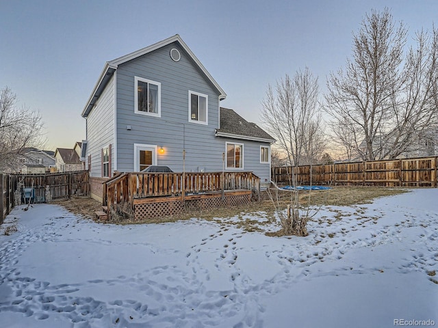 snow covered house with a trampoline and a wooden deck