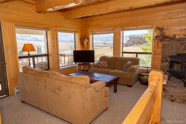 living room featuring wood ceiling, carpet, beamed ceiling, a wood stove, and wooden walls