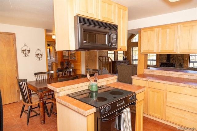 kitchen featuring light brown cabinetry, black appliances, and light tile patterned flooring