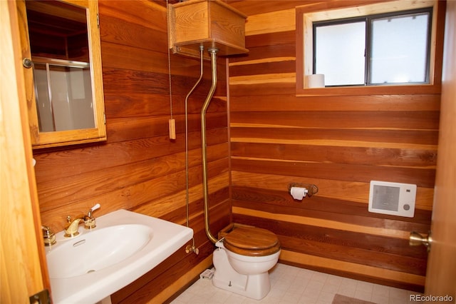 bathroom with sink, wooden walls, a shower with shower door, and toilet