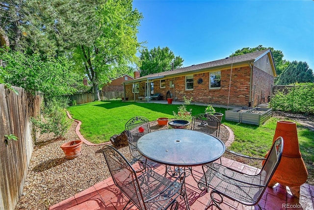 12348 Elizabeth Ct, Thornton, CO 80241 - back of house featuring a garden, brick siding, and a patio area