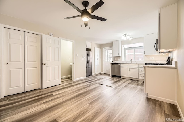 kitchen with ceiling fan, light hardwood / wood-style floors, white cabinetry, and stainless steel appliances