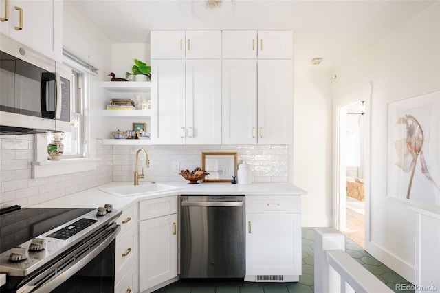 kitchen with appliances with stainless steel finishes, white cabinets, tasteful backsplash, and sink