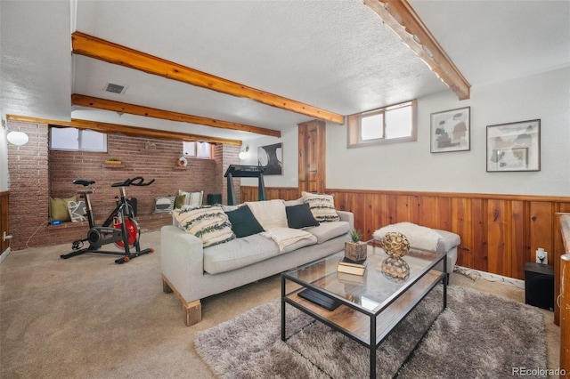 living room with brick wall, wooden walls, beamed ceiling, carpet floors, and a textured ceiling