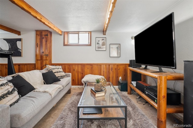 carpeted living room with a textured ceiling, beam ceiling, and wood walls