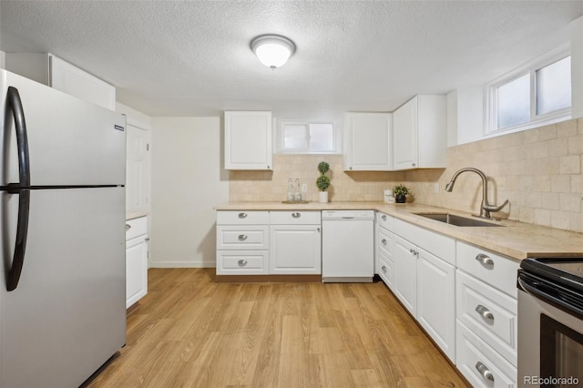 kitchen with sink, appliances with stainless steel finishes, white cabinetry, tasteful backsplash, and light wood-type flooring