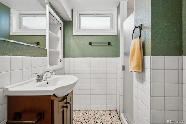 bathroom featuring walk in shower, vanity, and tile walls