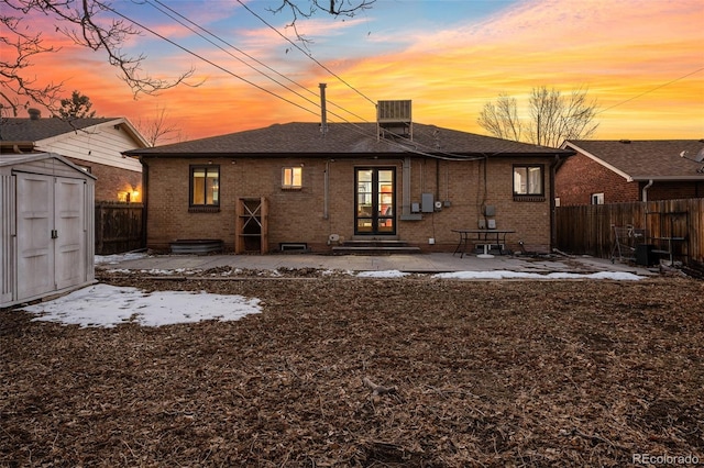 back house at dusk with a shed and a patio area