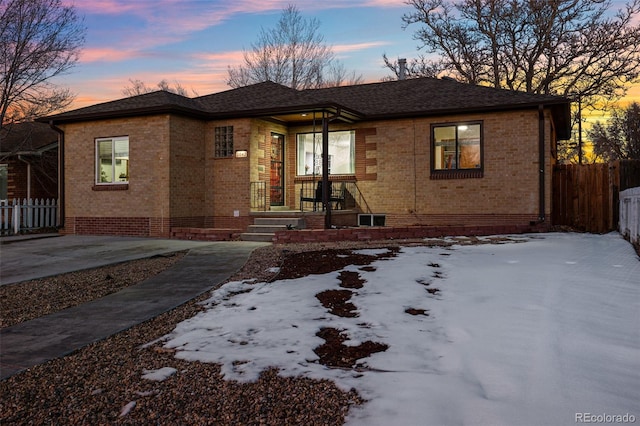 view of front of house with crawl space, brick siding, and fence