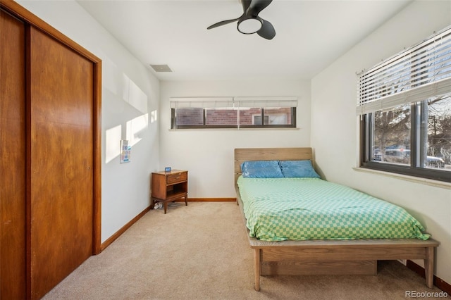 bedroom featuring visible vents, baseboards, ceiling fan, and light carpet