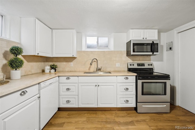 2042 Jamaica St, Aurora, CO 80010 - kitchen with appliances with stainless steel finishes, a sink, tasteful backsplash, white cabinets, and light countertops