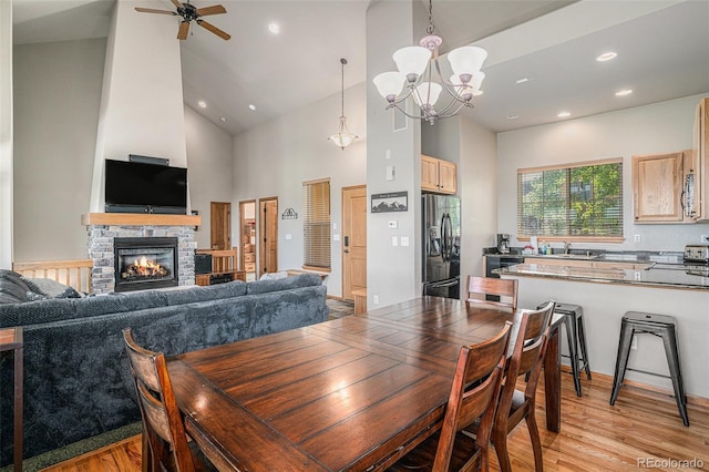 109 Peak Vw, Granby, CO 80446 - dining room featuring high vaulted ceiling, light wood-style flooring, a fireplace, a chandelier, and a ceiling fan