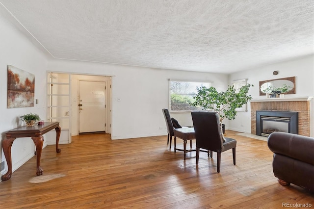 3201 S Albion St, Denver, CO 80222 - living area with light wood-style flooring, a textured ceiling, a fireplace, and baseboards